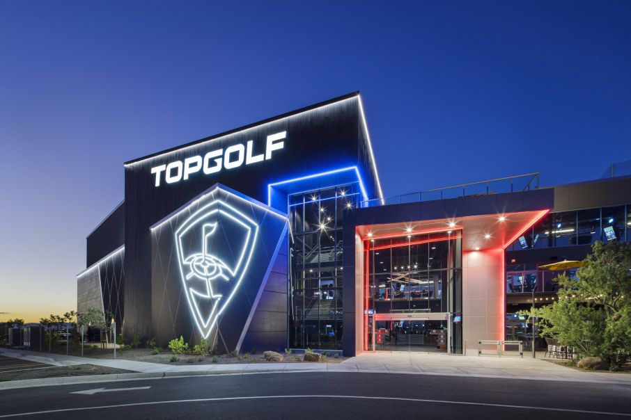 A nighttime view of Topgolf Schaumburg at 90 North, featuring bold neon lights, modern architecture, and a welcoming entrance.